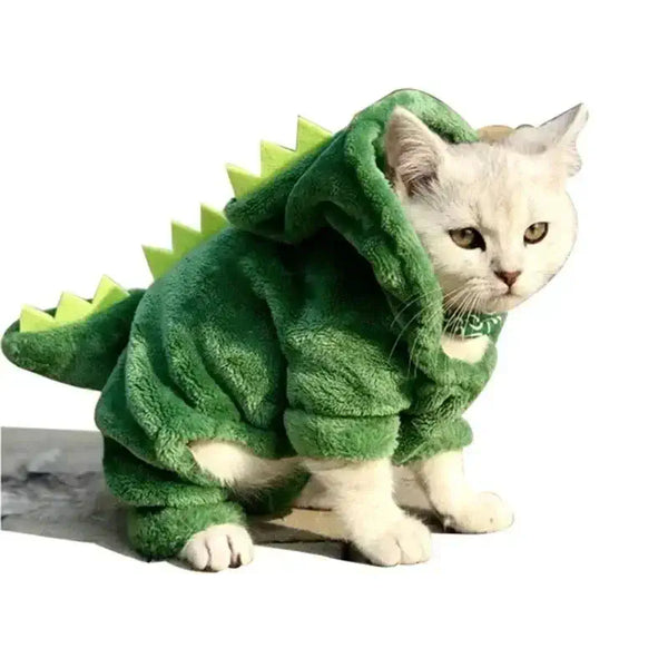 Chat blanc portant un costume de dinosaure confortable en polaire pour chats, idéal pour le divertissement et les occasions spéciales.